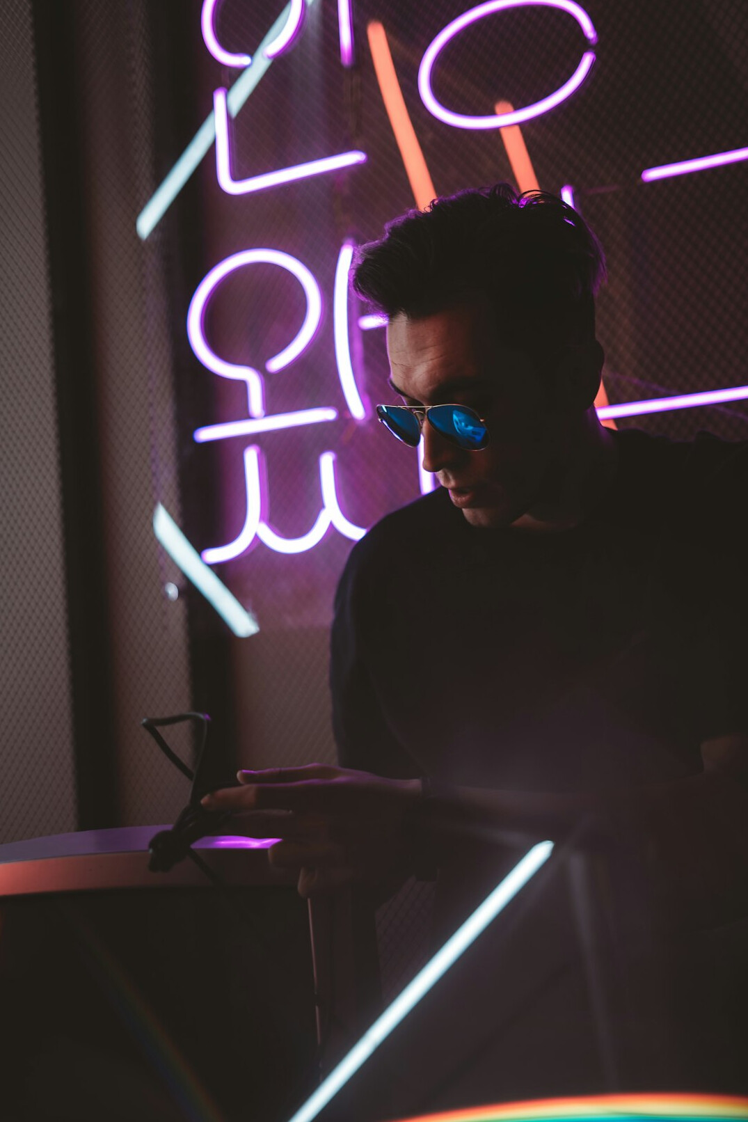 Young man typing code on a laptop at night with colorful screen glow